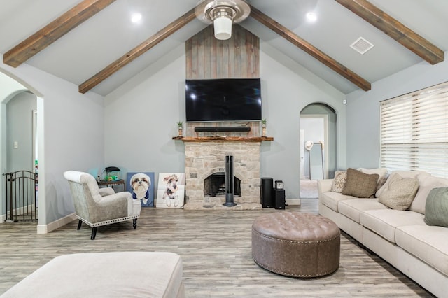 living room featuring a stone fireplace, high vaulted ceiling, ceiling fan, and light wood-type flooring