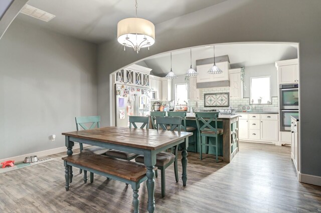 dining room with hardwood / wood-style flooring, vaulted ceiling, and a healthy amount of sunlight