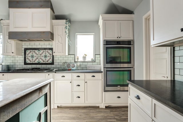 kitchen featuring tasteful backsplash, appliances with stainless steel finishes, custom range hood, and white cabinets