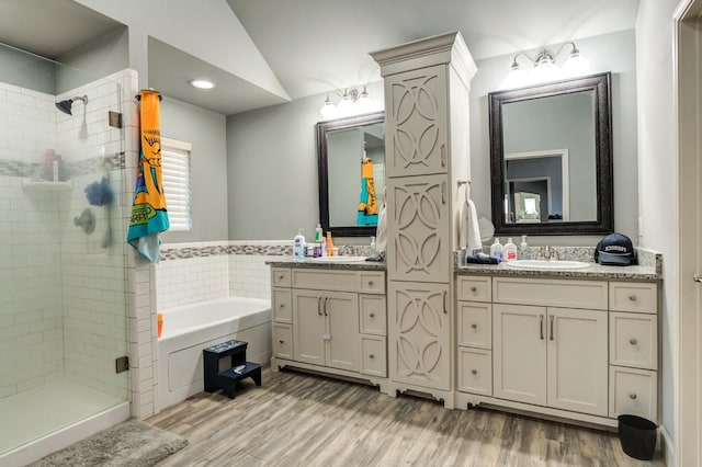 bathroom with hardwood / wood-style flooring, plus walk in shower, lofted ceiling, and vanity