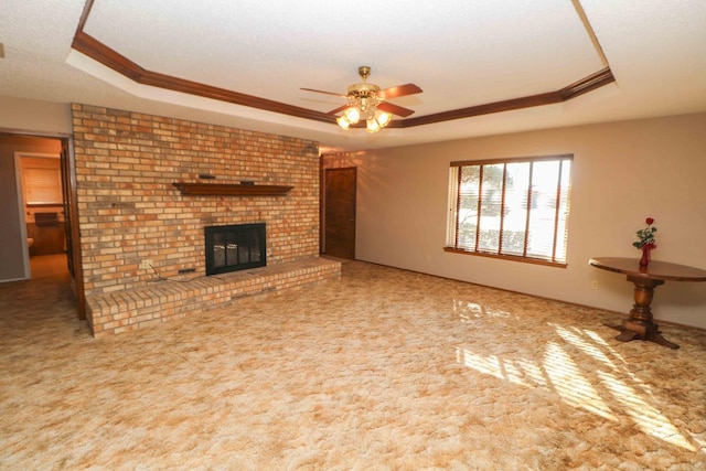 unfurnished living room with a fireplace, ceiling fan, a raised ceiling, crown molding, and a textured ceiling