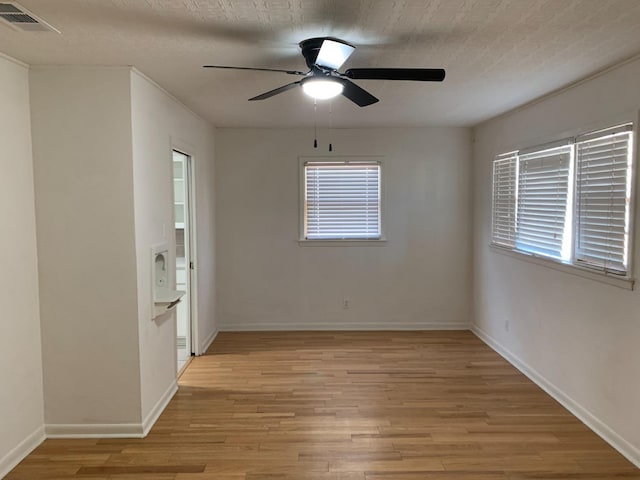 spare room featuring a textured ceiling, ceiling fan, and light hardwood / wood-style flooring