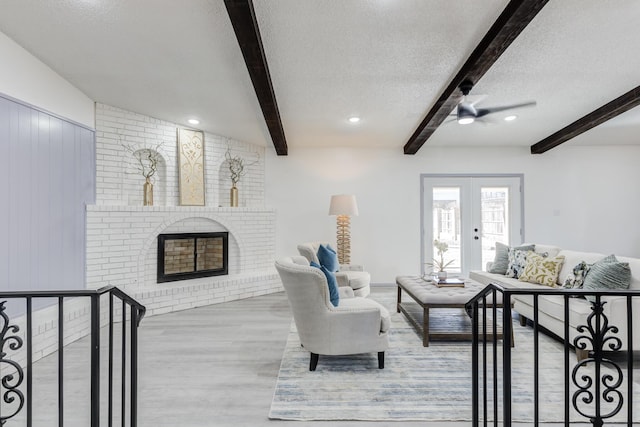 living room with french doors, a fireplace, beam ceiling, and a textured ceiling