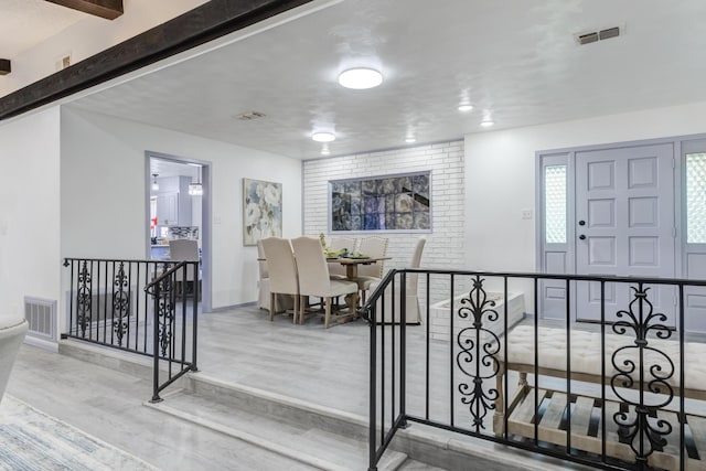 foyer featuring beamed ceiling and wood-type flooring