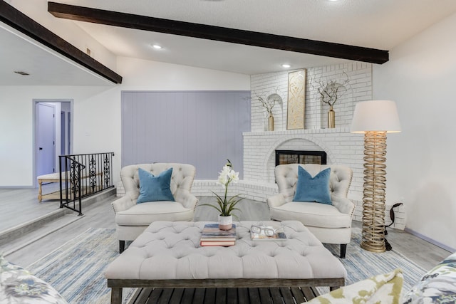 living room with vaulted ceiling with beams, a fireplace, and light hardwood / wood-style flooring