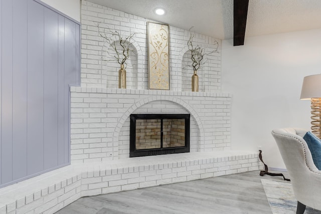 details with hardwood / wood-style floors, a fireplace, beam ceiling, and a textured ceiling