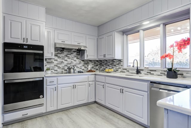 kitchen with sink, white cabinets, backsplash, light hardwood / wood-style floors, and stainless steel appliances