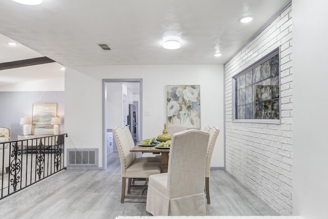 dining area with brick wall and light hardwood / wood-style floors