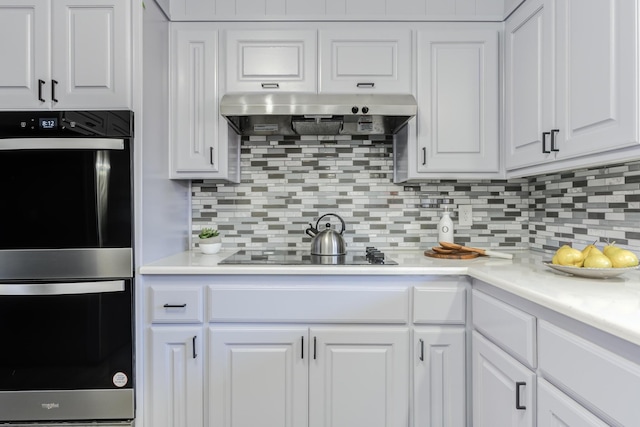 kitchen featuring white cabinetry, tasteful backsplash, double oven, black electric stovetop, and exhaust hood