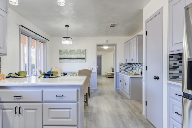 kitchen with pendant lighting, light hardwood / wood-style floors, and backsplash