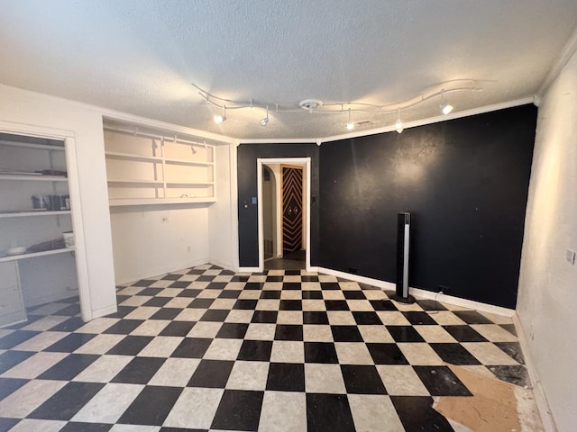 interior space with rail lighting, ornamental molding, and a textured ceiling