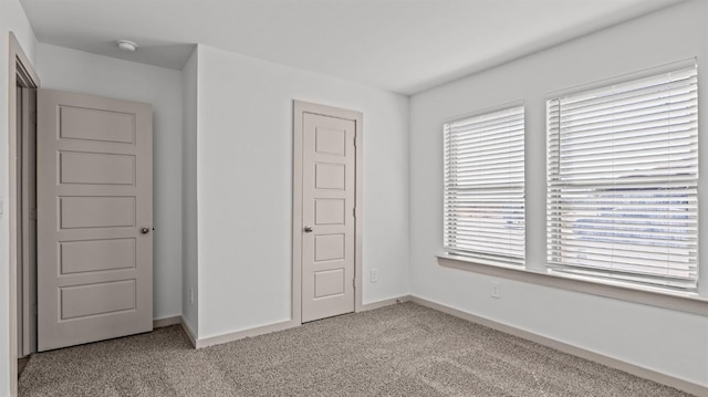 unfurnished bedroom featuring light colored carpet and a closet