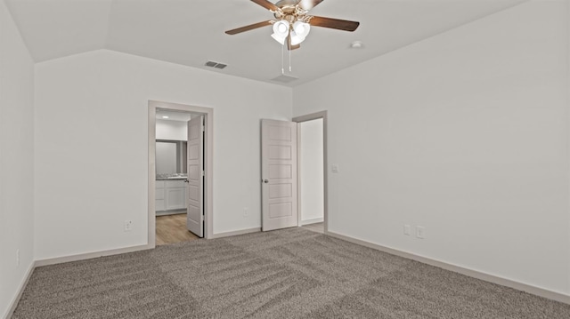 unfurnished bedroom with lofted ceiling, connected bathroom, light colored carpet, and ceiling fan