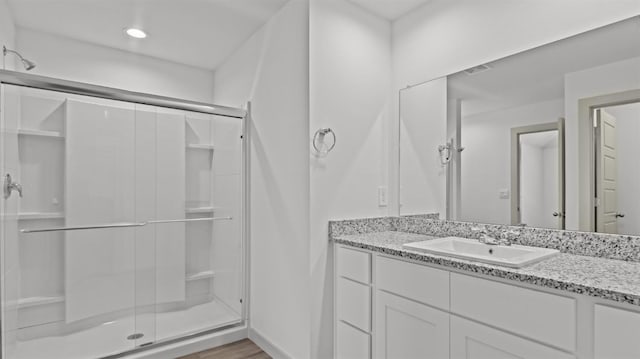 bathroom with vanity, hardwood / wood-style flooring, and a shower with door