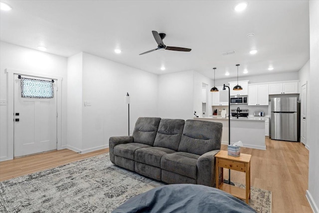 living room featuring light hardwood / wood-style flooring and ceiling fan