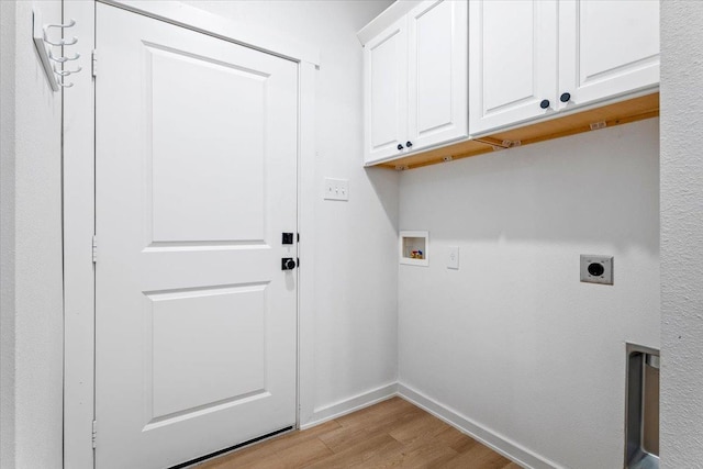 clothes washing area with electric dryer hookup, washer hookup, cabinets, and light wood-type flooring