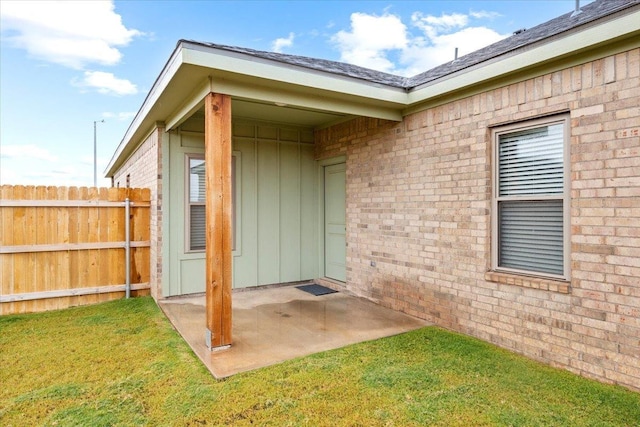 view of exterior entry featuring a lawn and a patio area