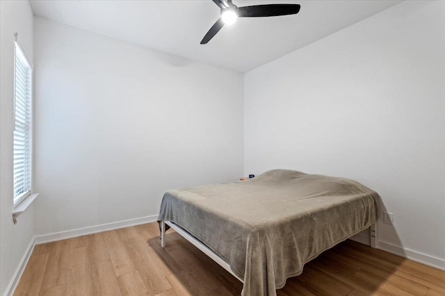 bedroom with ceiling fan, wood-type flooring, and multiple windows