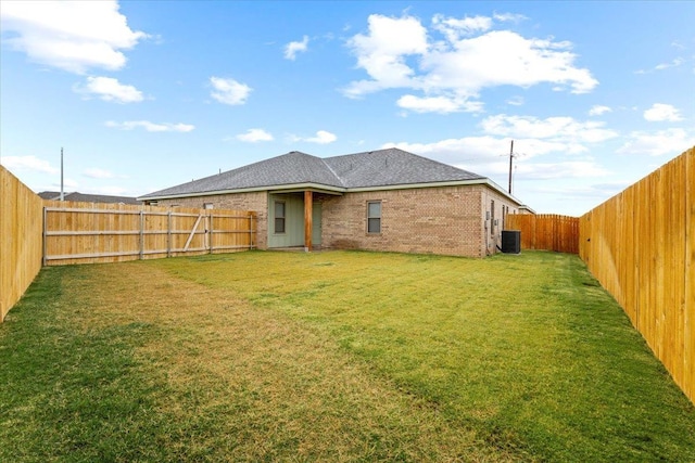 rear view of property featuring a yard and central AC unit