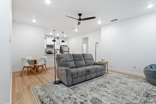 living room featuring ceiling fan and light wood-type flooring