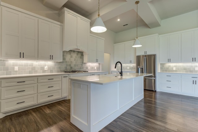 4603 140th St, Lubbock, TX 79424 - kitchen featuring appliances with stainless steel finishes, dark wood-type flooring, decorative backsplash, light countertops, and a kitchen island with sink