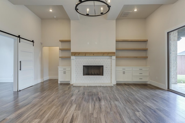 4603 140th St, Lubbock, TX 79424 - unfurnished living room with wood finished floors, a chandelier, a barn door, and a tile fireplace