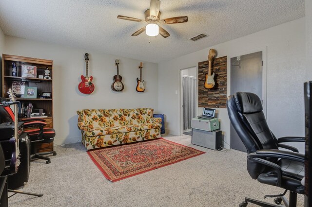 office area with light carpet, ceiling fan, and a textured ceiling