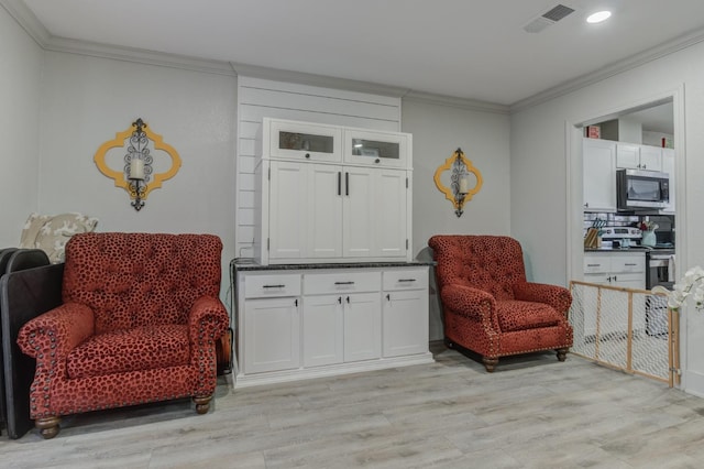 sitting room with ornamental molding and light wood-type flooring