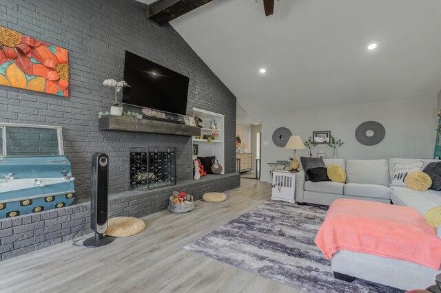 living room with beam ceiling, hardwood / wood-style flooring, a fireplace, and high vaulted ceiling