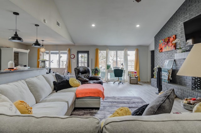 living room featuring a fireplace, high vaulted ceiling, and light wood-type flooring