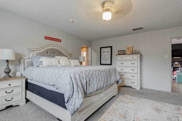 bedroom with light carpet, ceiling fan, and a textured ceiling