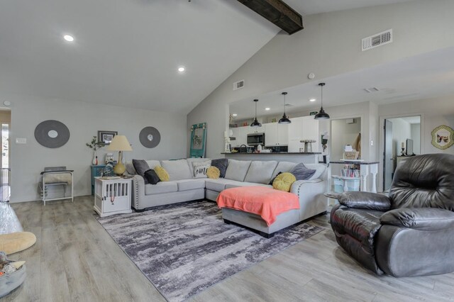 living room with high vaulted ceiling, beam ceiling, and light hardwood / wood-style floors