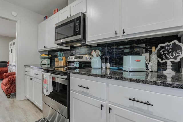 kitchen featuring tasteful backsplash, stainless steel appliances, dark stone counters, and white cabinets