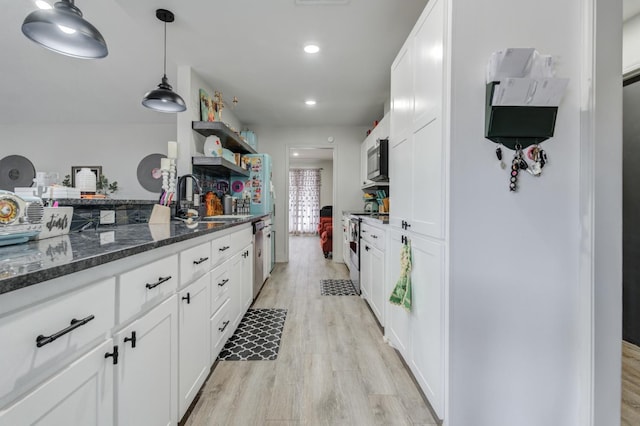 kitchen featuring sink, appliances with stainless steel finishes, light hardwood / wood-style floors, white cabinets, and decorative light fixtures