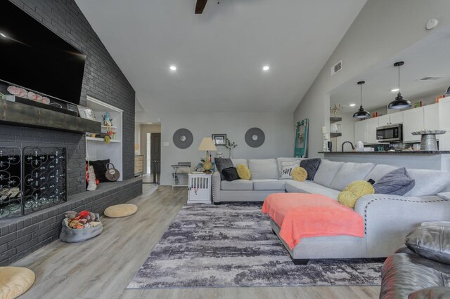 living room with a fireplace, light hardwood / wood-style flooring, and high vaulted ceiling