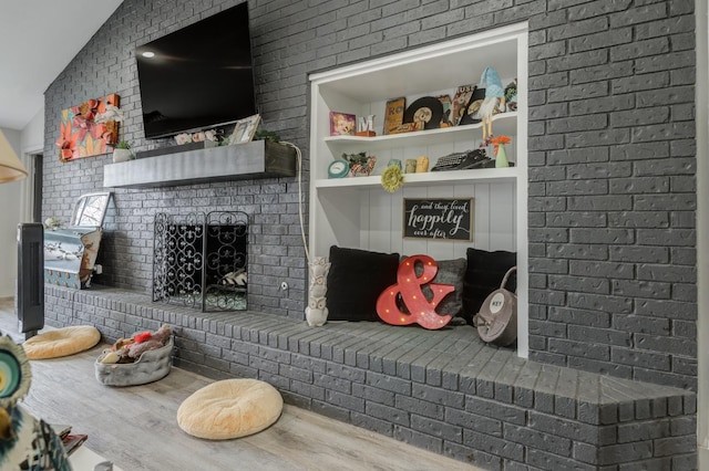 living room featuring lofted ceiling, a brick fireplace, and hardwood / wood-style flooring