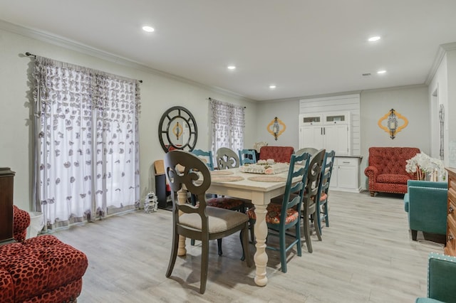 dining area with ornamental molding and light hardwood / wood-style floors