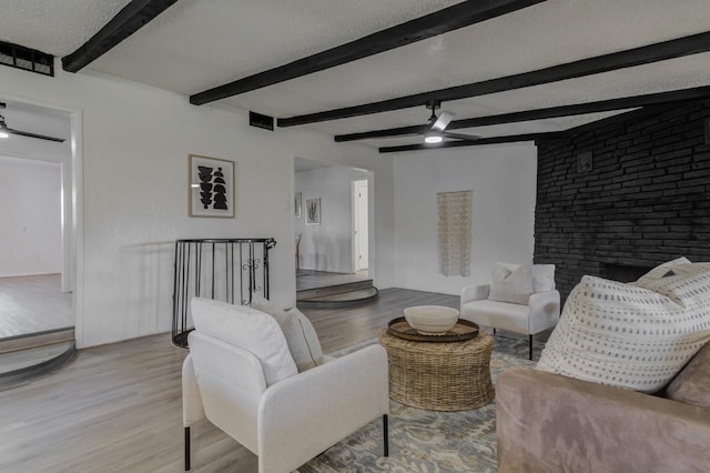 living room with light wood-type flooring, visible vents, ceiling fan, and a textured ceiling