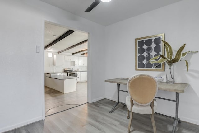 home office featuring a ceiling fan, light wood-style flooring, baseboards, and beamed ceiling