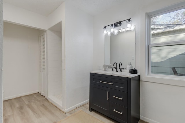 bathroom with a closet, vanity, baseboards, and wood finished floors