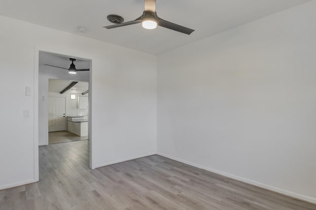 spare room with ceiling fan, light wood-style flooring, and baseboards