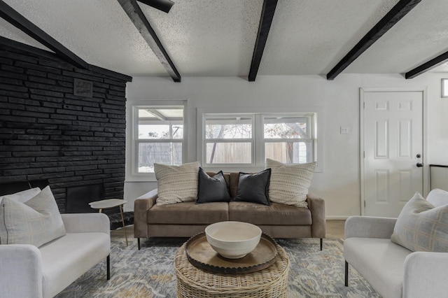 living area featuring a fireplace, wood finished floors, a textured ceiling, and beamed ceiling