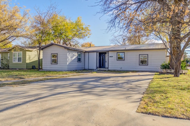 ranch-style house featuring metal roof, concrete driveway, and a front yard