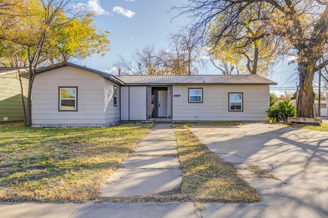 ranch-style house with metal roof and a front yard