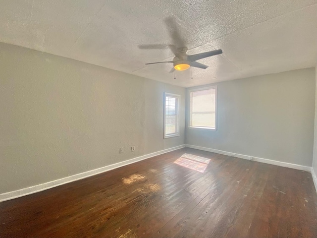 empty room with ceiling fan, dark wood-type flooring, and a textured ceiling