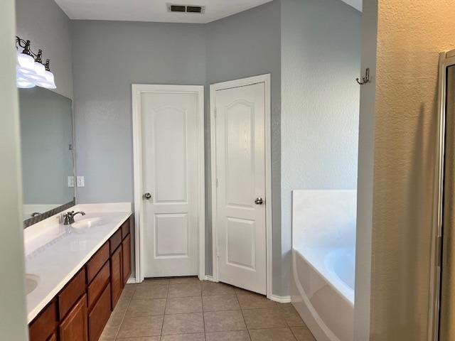 bathroom featuring vanity, a bath, and tile patterned floors