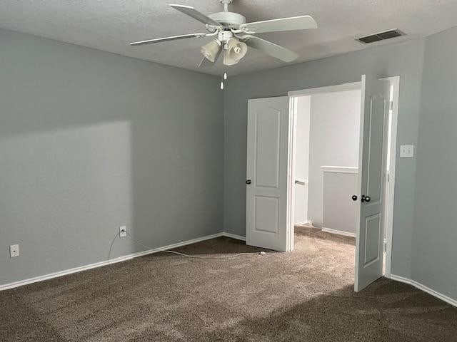 unfurnished bedroom featuring ceiling fan, a textured ceiling, and dark carpet