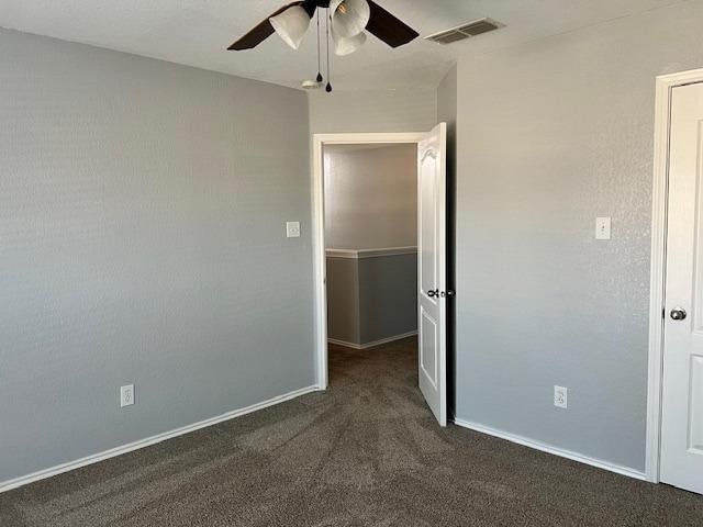 interior space with dark carpet and ceiling fan