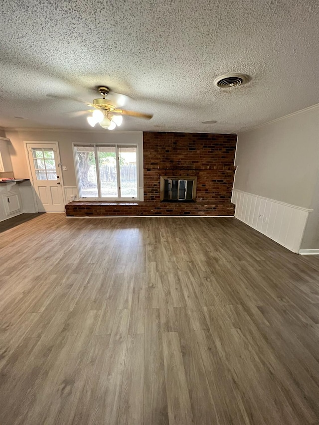 unfurnished living room with ceiling fan, wood-type flooring, a brick fireplace, and a textured ceiling