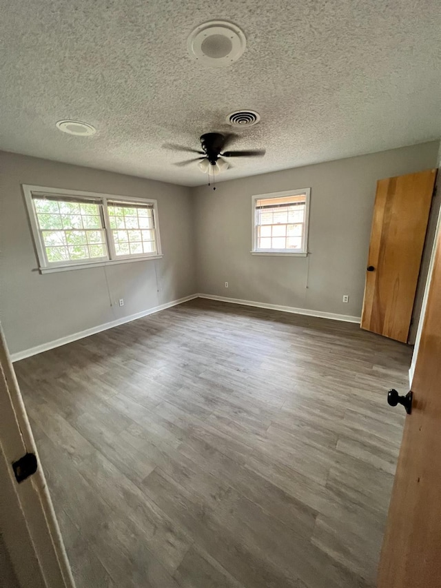 empty room with ceiling fan, dark wood-type flooring, and a textured ceiling